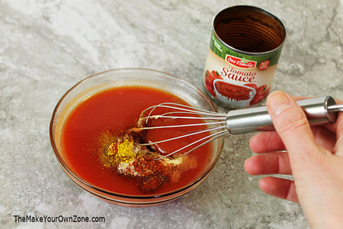 A bowl of homemade taco sauce being stirred with a whisk