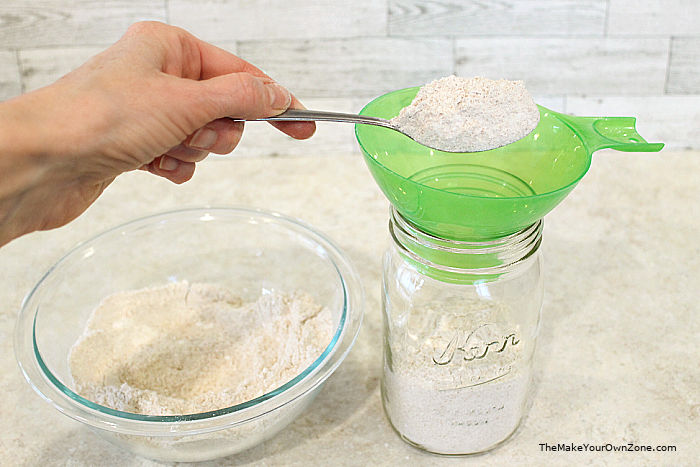 Using a funnel to put pancake mix in a jar