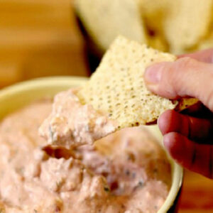 dipping a tortialla chip in homemade cream cheese salsa dip
