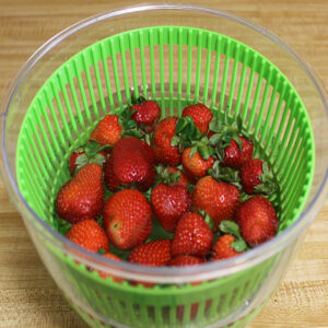 Strawberries in a salad spinner soaking in vinegar and water to make them last longer