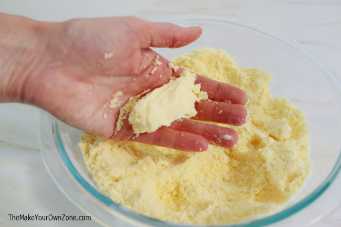 a hand holding the mixture for homemade bath bombs