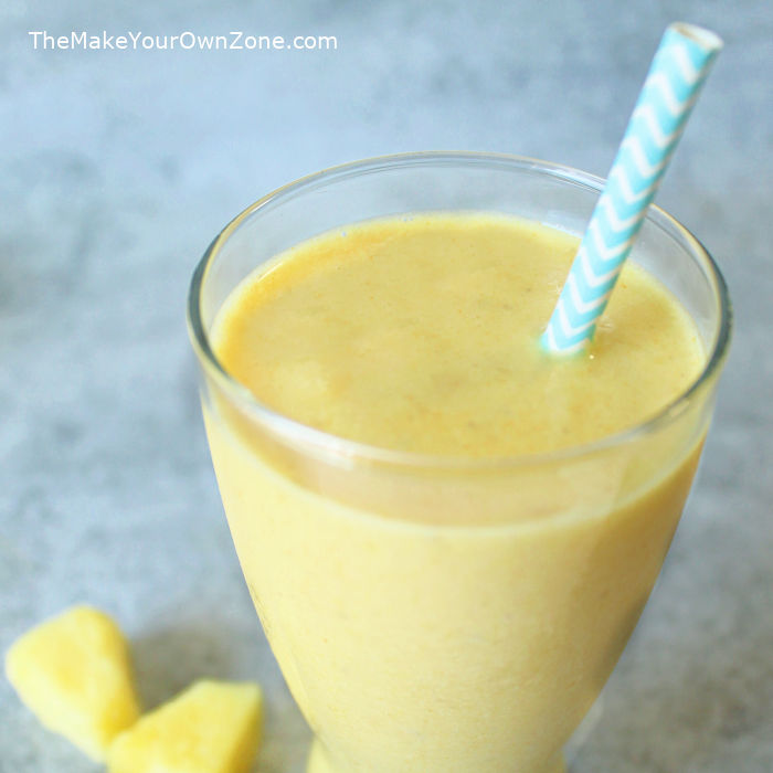 a yellow turmeric smoothie in a glass with straw