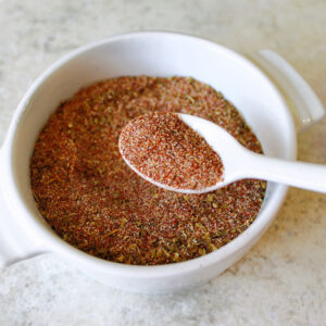 A small bowl of homemade 10-spice blend with a spoon.