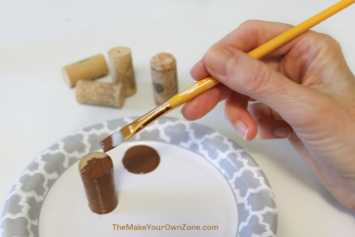 Painting a wine cork to use as a stem on a knitted pumpkin.