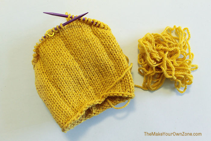 Using gold yarn to make a knit pumpkin on circular knitting needles.