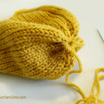 Gathering the stitches at the top of a knit pumpkin.