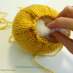 Putting stuffing into a homemade knit pumpkin.