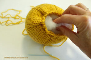 Putting stuffing into a homemade knit pumpkin.