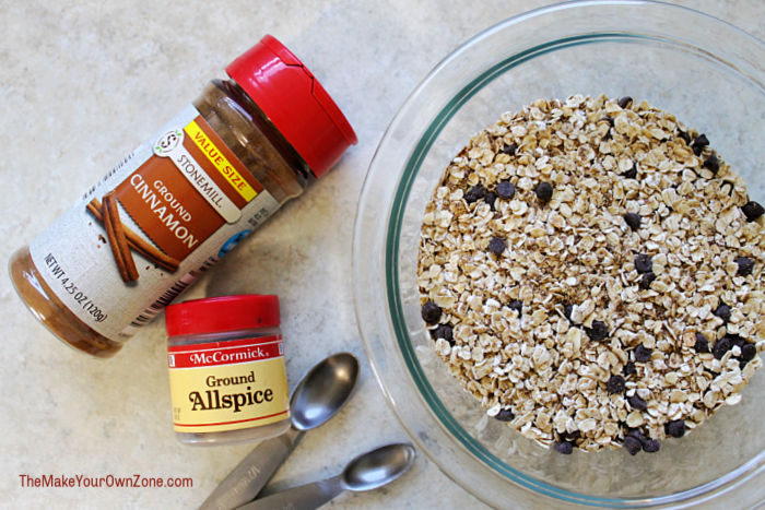 a bowl of oats and flax to make energy bites with jars of ground cinnamon and allspice.