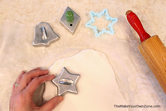 Using cookie cutters to make DIY white clay baking soda ornaments.