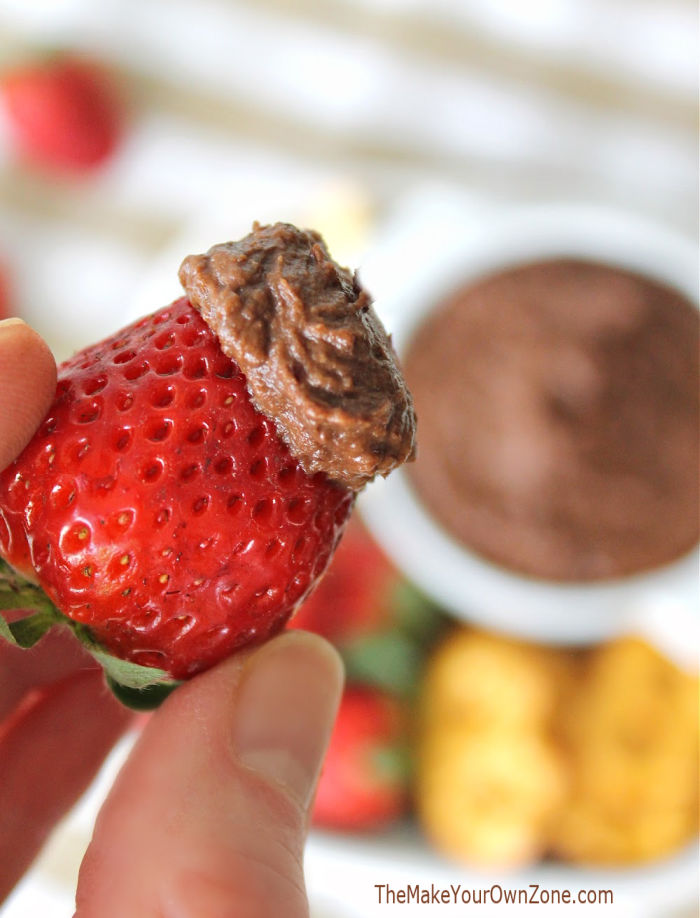 A strawberry dipped in chocolate hummus